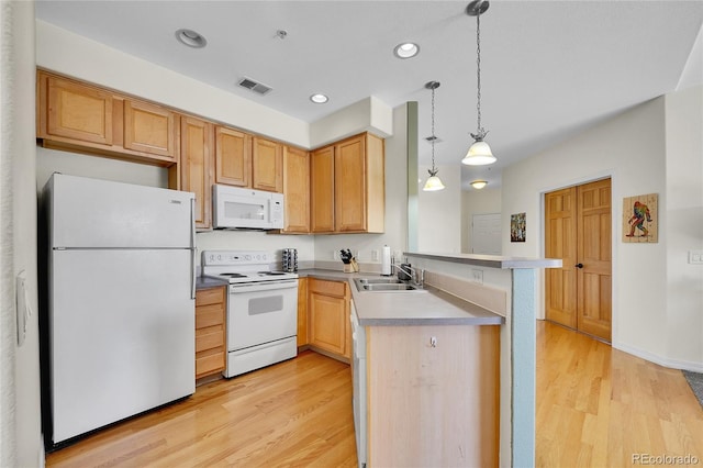 kitchen featuring a sink, white appliances, light wood-style floors, and a peninsula