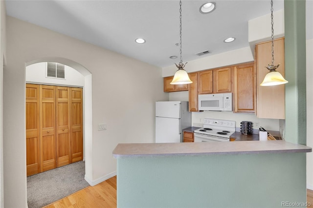 kitchen featuring visible vents, white appliances, arched walkways, and a peninsula