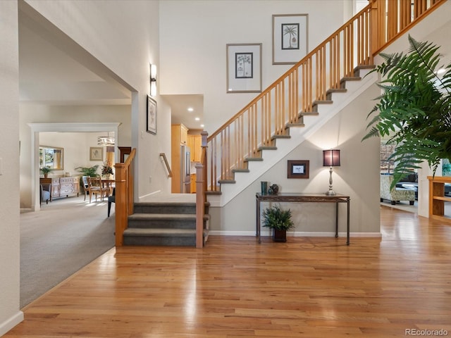 stairs with hardwood / wood-style floors and a towering ceiling