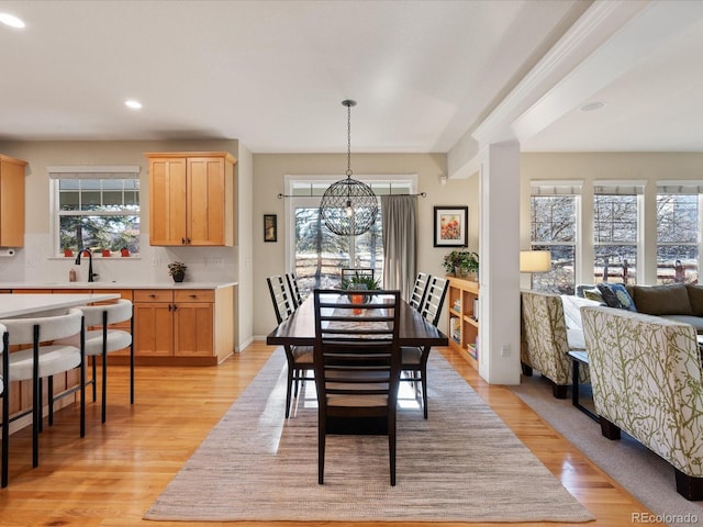 dining room featuring a healthy amount of sunlight, light hardwood / wood-style flooring, a chandelier, and sink