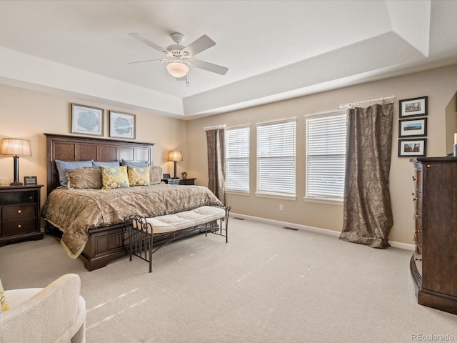 bedroom featuring light colored carpet, a raised ceiling, and ceiling fan