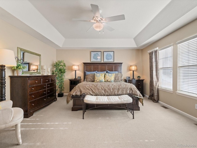 carpeted bedroom featuring a raised ceiling and ceiling fan