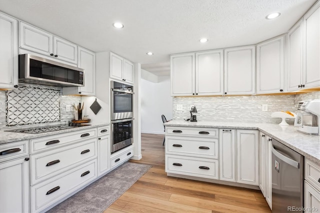 7822 W Ottawa Pl, Littleton, CO 80128 - kitchen with appliances with stainless steel finishes, light wood-style flooring, white cabinetry, recessed lighting, and tasteful backsplash