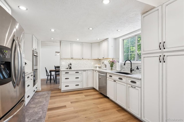 7822 W Ottawa Pl, Littleton, CO 80128 - kitchen featuring appliances with stainless steel finishes, a sink, light wood finished floors, decorative backsplash, and recessed lighting