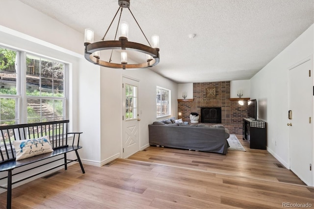 7822 W Ottawa Pl, Littleton, CO 80128 - living area with a textured ceiling, light wood-style flooring, a chandelier, a fireplace, and baseboards