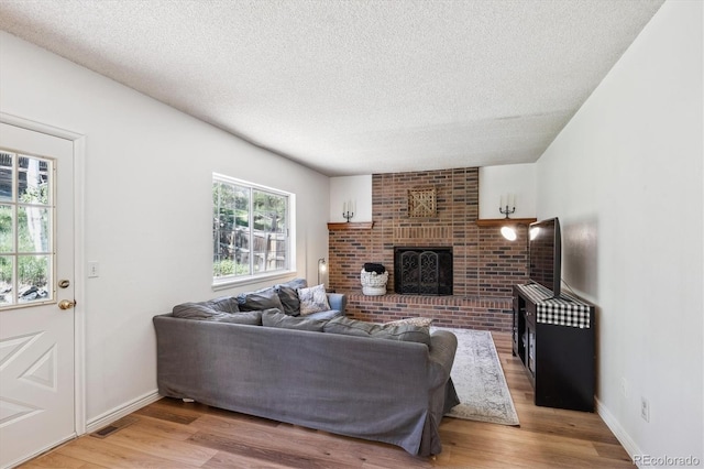 7822 W Ottawa Pl, Littleton, CO 80128 - living area featuring a textured ceiling, light wood finished floors, a fireplace, and baseboards
