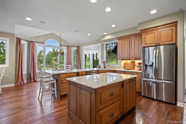 120 Silver Leaf Way, Castle Rock, CO 80108 - kitchen featuring appliances with stainless steel finishes, a peninsula, brown cabinetry, light stone countertops, and lofted ceiling