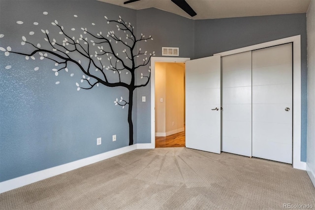 unfurnished bedroom featuring ceiling fan, vaulted ceiling, carpet floors, and a closet