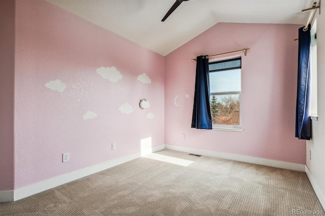 spare room featuring ceiling fan, light colored carpet, and vaulted ceiling