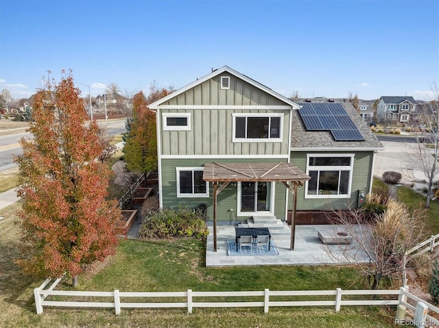 back of house featuring a lawn, solar panels, and a patio area