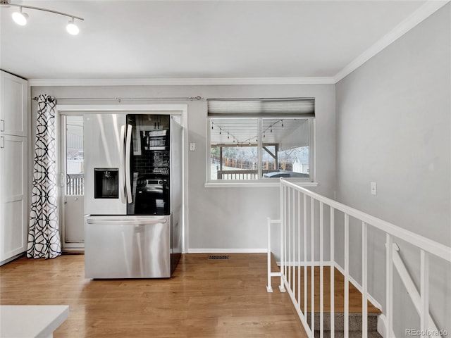 kitchen featuring baseboards, stainless steel fridge with ice dispenser, white cabinets, crown molding, and light wood-type flooring