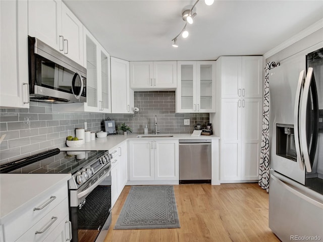 kitchen with light countertops, white cabinets, appliances with stainless steel finishes, and a sink