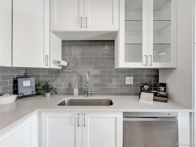 kitchen with stainless steel dishwasher, decorative backsplash, white cabinets, and a sink