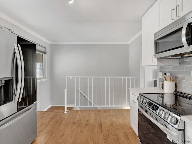 kitchen featuring white cabinetry, crown molding, light wood-style floors, and stainless steel appliances