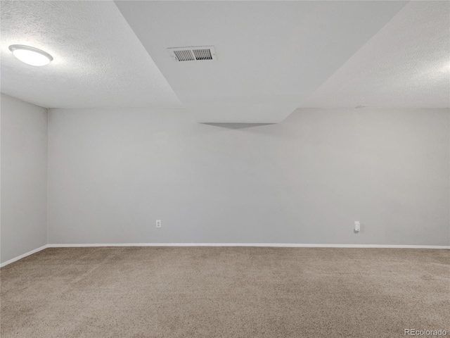 spare room with baseboards, visible vents, carpet floors, and a textured ceiling