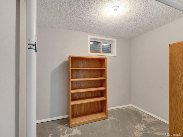 interior space featuring baseboards, a textured ceiling, and concrete floors