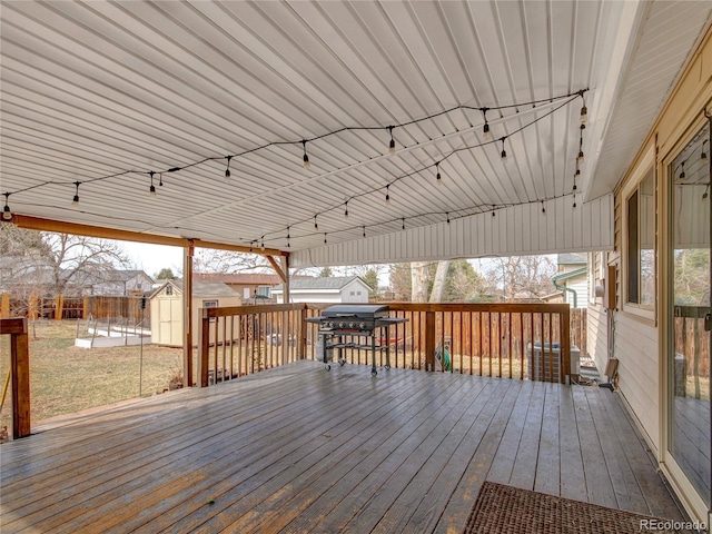 deck featuring a shed, a grill, an outdoor structure, and fence