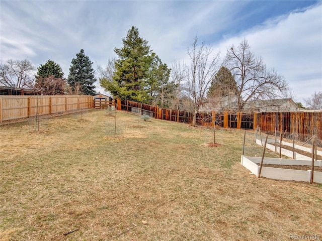 view of yard with an outbuilding, a vegetable garden, and a fenced backyard