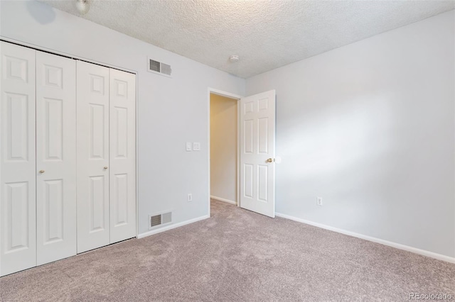 unfurnished bedroom featuring a closet, a textured ceiling, and carpet floors