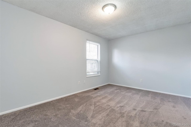 unfurnished room with a textured ceiling and carpet flooring