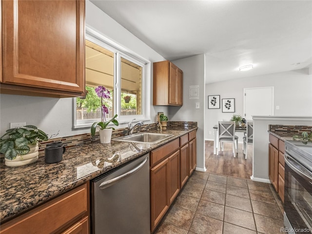 5995 Estes St, Arvada, CO 80004 - kitchen featuring stainless steel appliances, a sink, brown cabinetry, dark stone counters, and baseboards