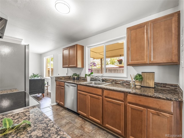 5995 Estes St, Arvada, CO 80004 - kitchen with stainless steel appliances, brown cabinetry, a sink, and dark stone countertops