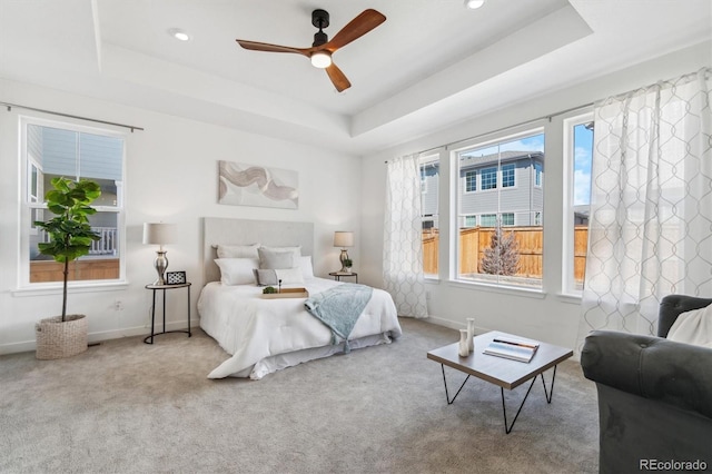 bedroom with a raised ceiling, carpet flooring, and multiple windows