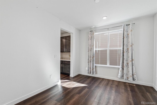 spare room with plenty of natural light, visible vents, baseboards, and wood finished floors