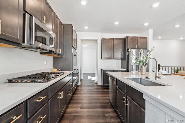 kitchen featuring dark brown cabinetry, recessed lighting, a sink, appliances with stainless steel finishes, and dark wood finished floors