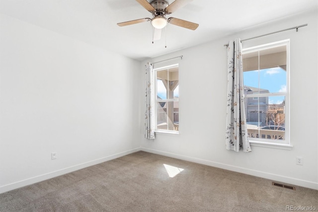 spare room featuring carpet, a healthy amount of sunlight, and visible vents