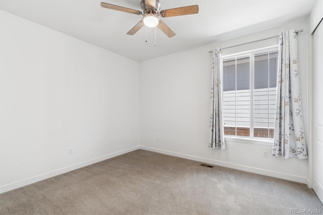 empty room with carpet, visible vents, and baseboards