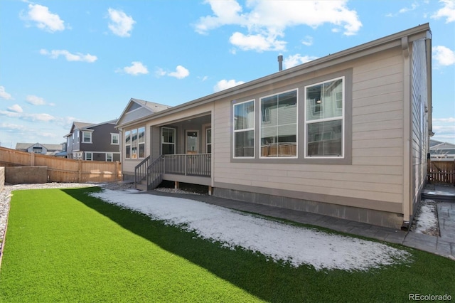 rear view of property featuring fence and a yard