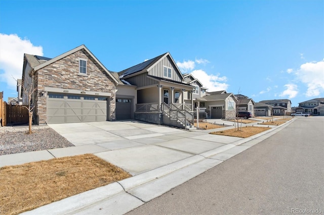 view of front facade featuring solar panels, fence, stone siding, driveway, and board and batten siding