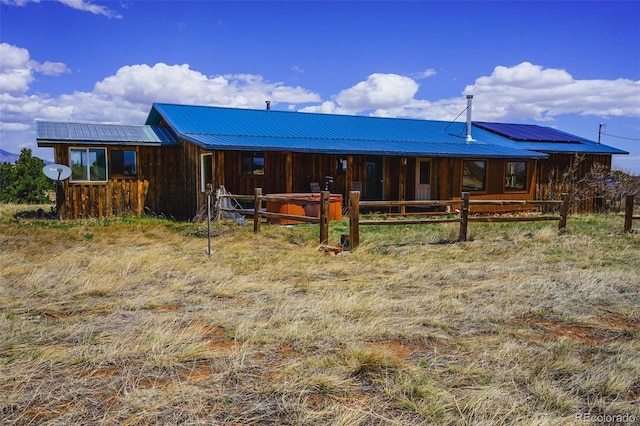 rear view of property with an exterior structure, metal roof, and an outdoor structure