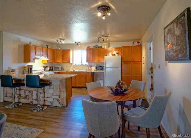 kitchen featuring range, a peninsula, stainless steel microwave, under cabinet range hood, and freestanding refrigerator