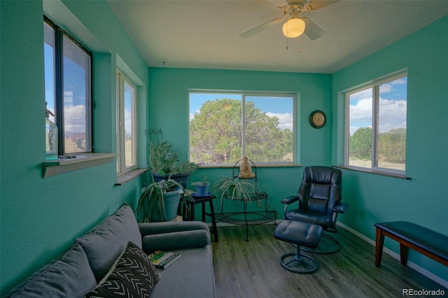 living area featuring baseboards, wood finished floors, and a ceiling fan