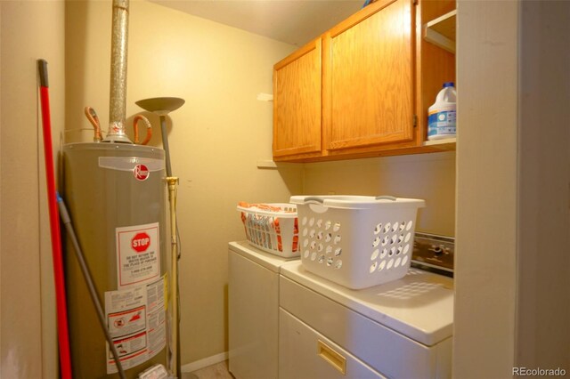 washroom featuring water heater, washing machine and clothes dryer, and cabinet space