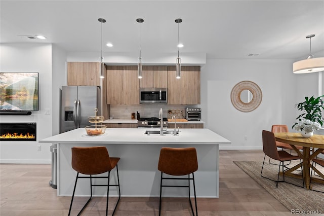 kitchen featuring a sink, appliances with stainless steel finishes, tasteful backsplash, modern cabinets, and a kitchen bar