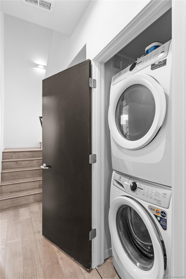 washroom with laundry area, stacked washer / dryer, and visible vents