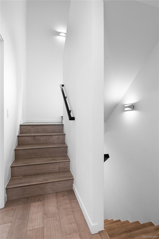 stairs with wood finished floors and baseboards