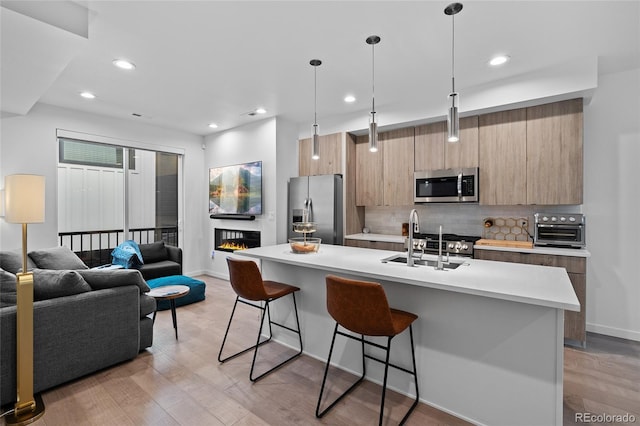 1930 Hooker St Unit 3, Denver, CO 80204 - kitchen featuring appliances with stainless steel finishes, a kitchen bar, modern cabinets, light countertops, and an island with sink