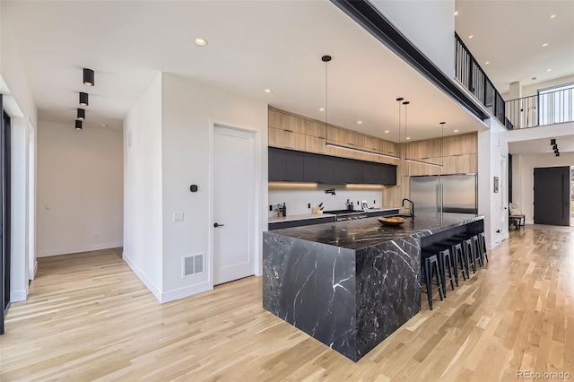 kitchen with light wood-type flooring, visible vents, modern cabinets, and built in fridge