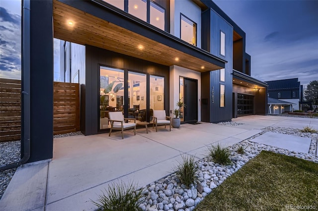 rear view of house with driveway, a patio area, and a garage