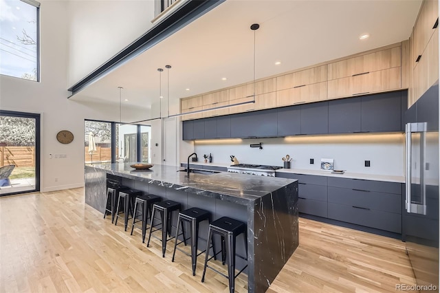 kitchen featuring modern cabinets, a sink, a kitchen breakfast bar, built in refrigerator, and light wood-style floors