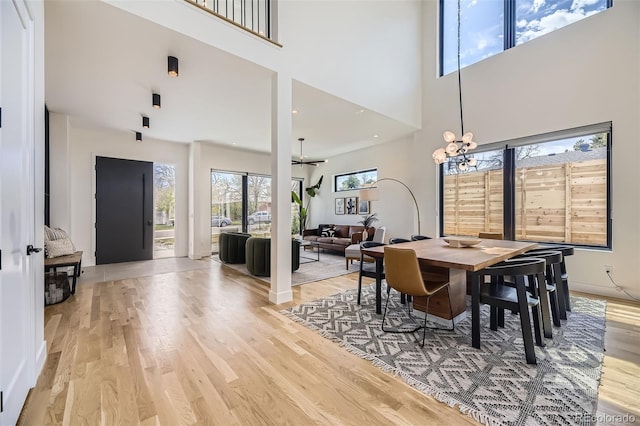 dining room featuring light wood-type flooring and a towering ceiling
