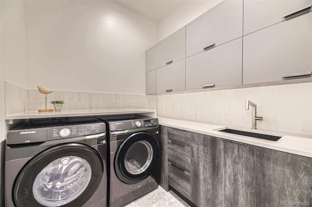 washroom featuring cabinet space, washing machine and dryer, tile walls, and a sink