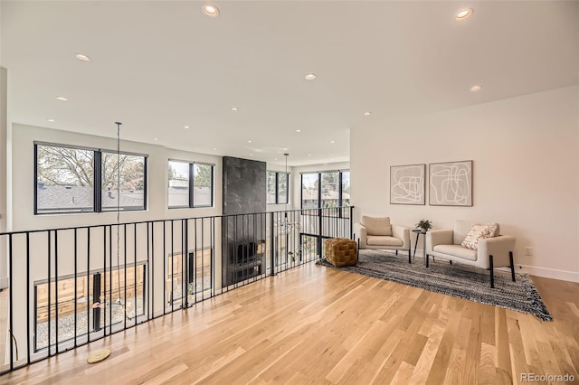 living area with baseboards, a wealth of natural light, light wood-style flooring, and recessed lighting