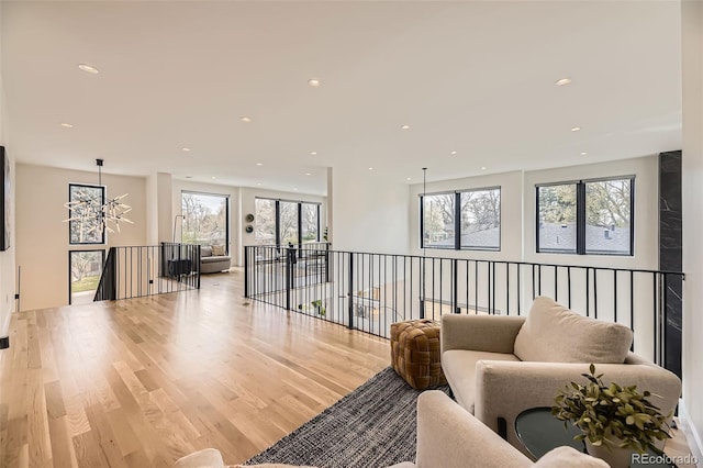 living room with an inviting chandelier, light wood-style flooring, a wealth of natural light, and recessed lighting