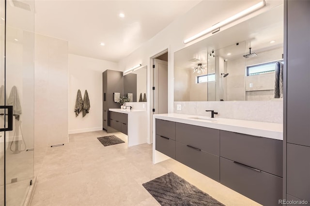 full bath with a stall shower, ceiling fan, two vanities, and a sink
