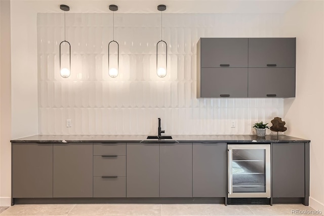 bar featuring a sink, decorative light fixtures, backsplash, beverage cooler, and baseboards